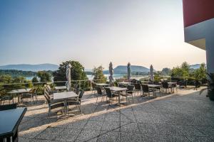 - un ensemble de tables et de chaises sur une terrasse dans l'établissement Hotel Faaker See Inn by S4Y, à Faak am See