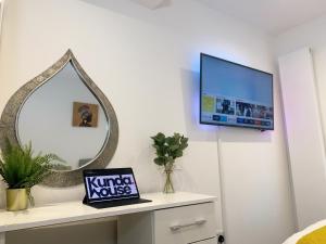 a room with a mirror and a tv on a wall at Kunda House Selly Oak in Birmingham