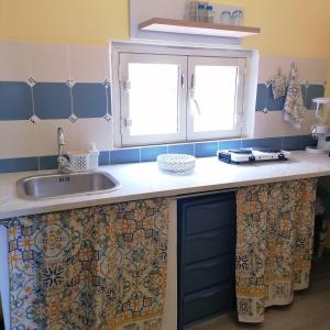 un bancone della cucina con lavandino e due finestre di Casa Giusitta a Catania
