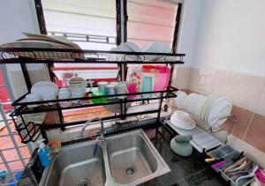 a kitchen with a sink and a shelf with dishes at Grandmaa Homestay, Seberang Takir in Kuala Terengganu