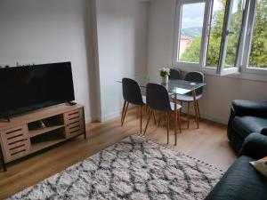 uma sala de estar com uma televisão e uma mesa e cadeiras em Apartamento familiar con vistas a la montaña en Zarautz em Zarautz