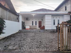 une petite maison blanche avec une allée en briques dans l'établissement Reddoorz Syariah Near Kantor Gubernur Jambi, à Jambi