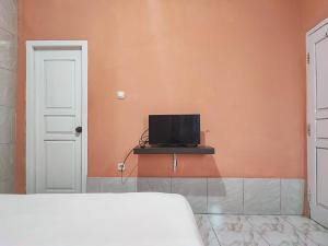 a bedroom with a bed and a tv on a wall at Reddoorz Syariah Near Kantor Gubernur Jambi in Jambi