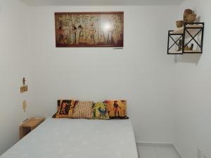 a white room with a bed with a painting on the wall at Casa do Léo 2 - Temática Egito e Japão in João Pessoa
