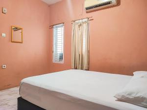 a bedroom with a large bed and a window at Reddoorz Syariah Near Kantor Gubernur Jambi in Jambi