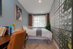 a bedroom with a bed and a desk and a wall at Raynes Park 2 Bedroom Haven in Raynes Park