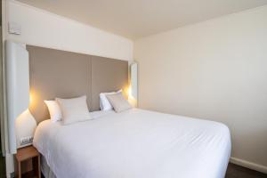 een slaapkamer met een groot wit bed met 2 kussens bij Campanile Reims Ouest - Tinqueux in Reims