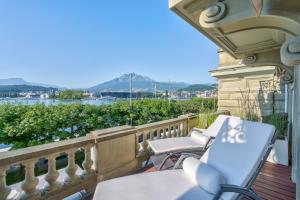 a balcony with chairs and a view of the water at Grand Hotel National Luzern in Luzern