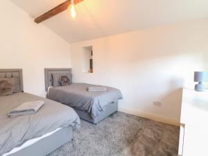 two beds in a room with white walls at Midway Cottage in Matlock