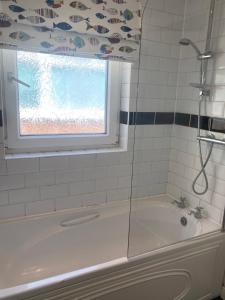 a bathroom with a shower and a tub with a window at Fisherman's Keep in Selby