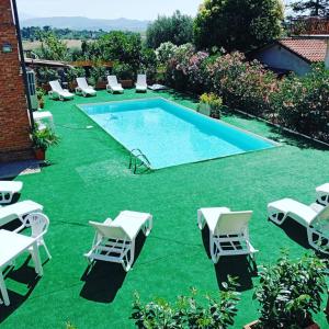 un patio trasero con piscina y césped verde en Villa Mezzetti, en Petrignano sul Lago