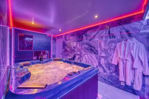 La grande salle de bains est pourvue d'une baignoire avec un éclairage violet. dans l'établissement Love Room Attitude, à Grenoble