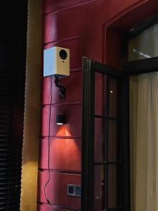 a room with a red wall with a speaker and a door at HOTEL le JARDIN SECRET saigon in Ho Chi Minh City
