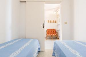 1 dormitorio con 2 camas y 1 silla en Vento d`estate by BarbarHouse, en Torre Pali