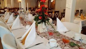 a long table with white tables with red flowers on it at Hotel Fritza - tidigare "Hotel Fritzatorpet" in Olofström