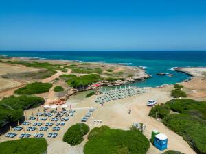 Calanca Apulian Residence في توري سانتا سابينا: اطلالة جوية على شاطئ فيه مظلات والمحيط