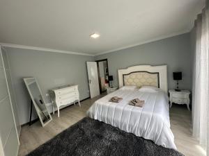 1 Schlafzimmer mit einem weißen Bett, 2 Tischen und einem Spiegel in der Unterkunft The Spot - ilha de São Miguel (Povoação) Açores in Povoação