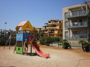 dos niños jugando en un tobogán en un parque infantil en Apartamentos Alcocebre Suites 3000, en Alcossebre