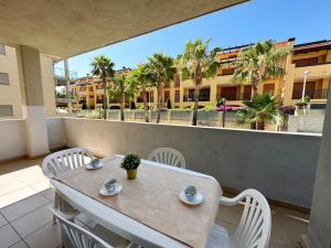 stół i krzesła na balkonie z palmami w obiekcie Apartamentos Alcocebre Suites 3000 w mieście Alcossebre