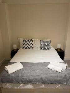 uma cama grande com duas almofadas e toalhas em City Apartments near Seven Sisters em Londres