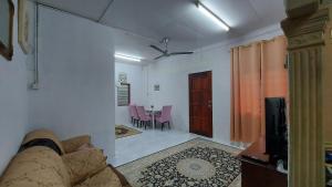 a living room with a couch and a dining room at SEROJA HOMESTAY in Baling