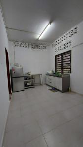 cocina grande con paredes blancas y suelo blanco en SEROJA HOMESTAY, en Baling