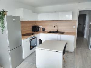 a kitchen with white cabinets and a white refrigerator at KEZA's Apartment - Strasbourg in Strasbourg