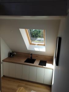 an attic kitchen with a sink and a window at Nendrės apartamentai in Nida