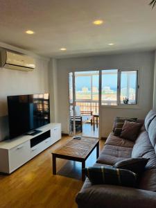 een woonkamer met een bank en een flatscreen-tv bij 3 Bedrooms Apt WITH THE SEA VIEW in Málaga