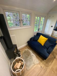 a living room with a blue couch and a fireplace at Lingfield Shepherds Hut in Blindley Heath