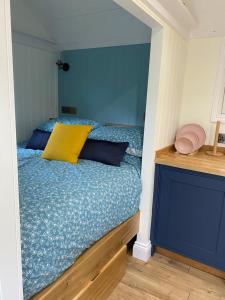 um quarto com uma cama com uma almofada amarela em Lingfield Shepherds Hut em Blindley Heath