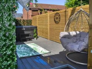 a backyard patio with a swing and a grill at Stunning Town Center Cottage with hot tub in Morpeth