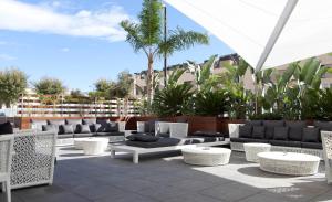 een patio met banken, stoelen en palmbomen bij Hotel SB Plaza Europa in Hospitalet de Llobregat