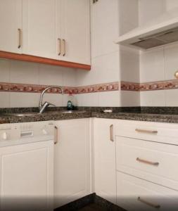 eine Küche mit weißen Schränken und einem Waschbecken in der Unterkunft Penthouse in Puerto Marina Benalmádena in Benalmádena