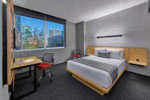 a hotel room with a bed and a desk and a window at City Express Plus by Marriott Santa Fe in Mexico City