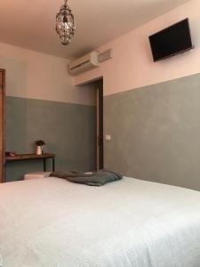 a bedroom with a white bed and a tv on the wall at B&B MELLONI STREET in Dolo