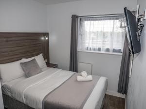 een slaapkamer met een bed met een handdoek erop bij Sky Nights Hotel London Heathrow in Hillingdon