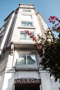 Ein hohes weißes Gebäude mit einem Schild auf dem Schild. in der Unterkunft Hotel Maroa Vigo in Vigo
