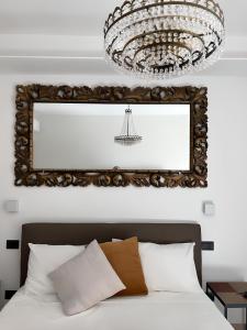 uno specchio sopra un letto con lampadario pendente di La Dimora Degli Angeli a Noto