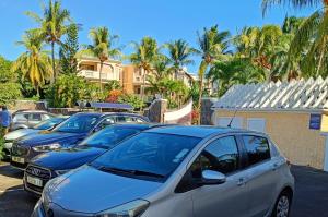a row of parked cars in a parking lot with palm trees at The Coastal Apartment in Flic-en-Flac