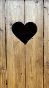 un trou en forme de cœur dans une clôture en bois dans l'établissement Romantic, lovely sauna house in Estonian Countryside near the lake!, à Soe