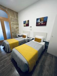 a room with two beds with yellow and gray sheets at Guest house D. Filipe I in Porto