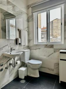 a bathroom with a toilet and a sink and a window at Guest house D. Filipe I in Porto