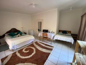 a bedroom with two beds and a table and a desk at El-Kole Bed and Breakfast in Tsumeb
