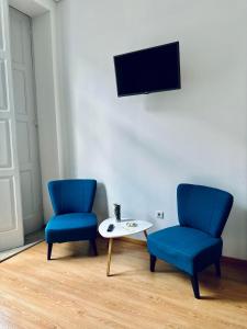 2 blaue Stühle, ein Tisch und ein TV in der Unterkunft Guest house D. Filipe I in Porto