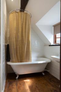 a white bath tub in a bathroom with a shower curtain at Bewdley River Cottage - Free private gated parking for 2 cars - River front location in Bewdley