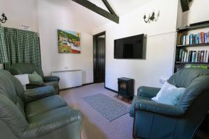 a living room with two chairs and a flat screen tv at Idyllic Cornish cottage in the beautiful Lamorna valley - walk to pub & sea in Paul