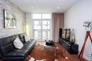 a living room with a black leather couch and a television at Fantastic City Centre Flat in Glasgow