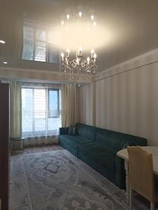 ein Wohnzimmer mit einem grünen Sofa und einem Kronleuchter in der Unterkunft Orion Apartment in Bischkek