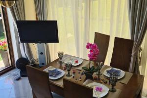 a dining room table with a television and flowers on it at Seagarden Villa Resort / Villa Dimar 2 in Lozenets